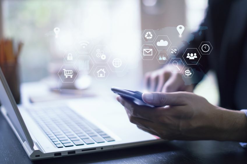 A person’s hands using a smartphone with various icons floating above it, representing digital services