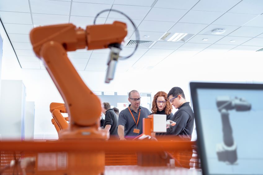 Orange robotic machine in foreground, businesspeople in background