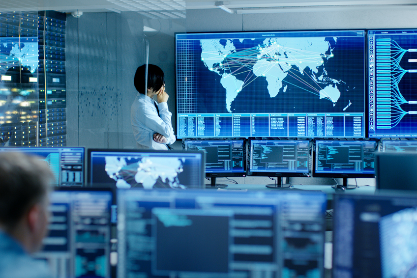 Businessman in control center looking at world map on screen