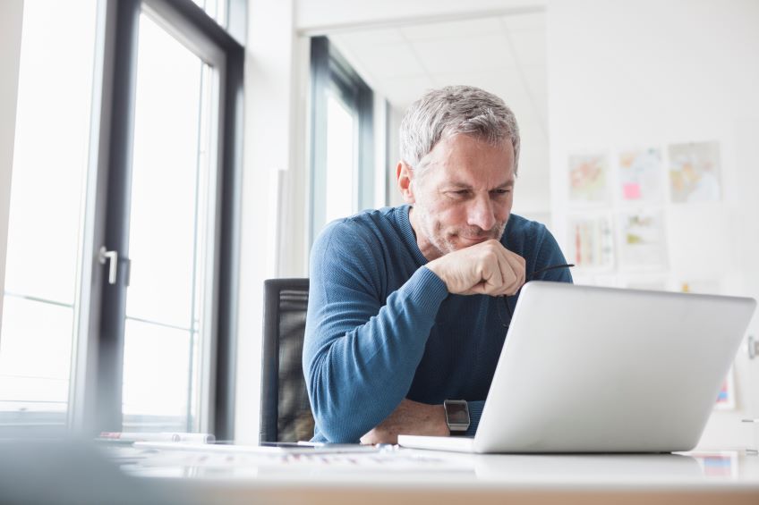 man intently looking at laptop screen