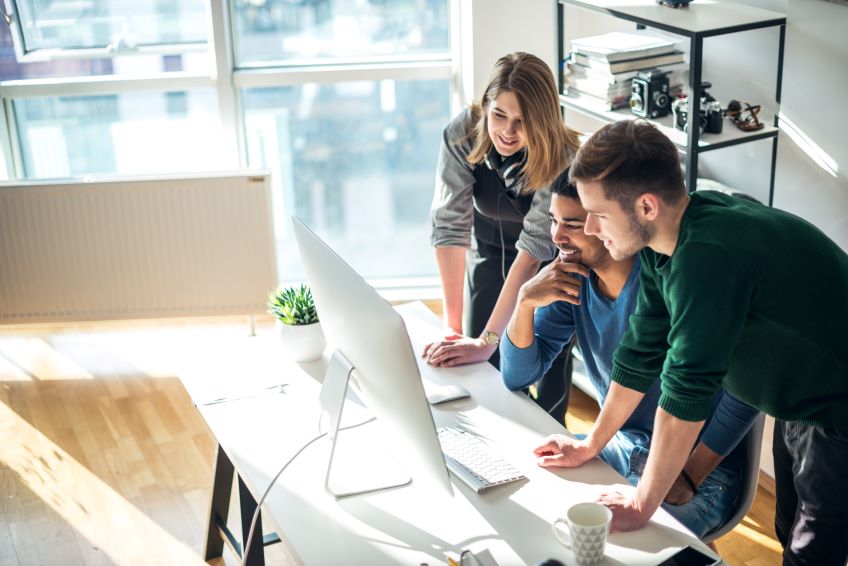 Three people gathered around a desktop computer