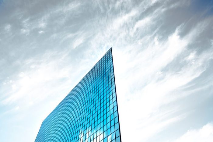 Image of a tall glass building in front of blue sky