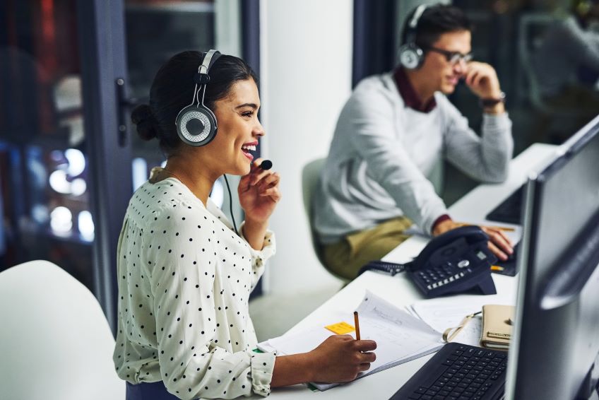 Woman at call center smiles while on her headset.