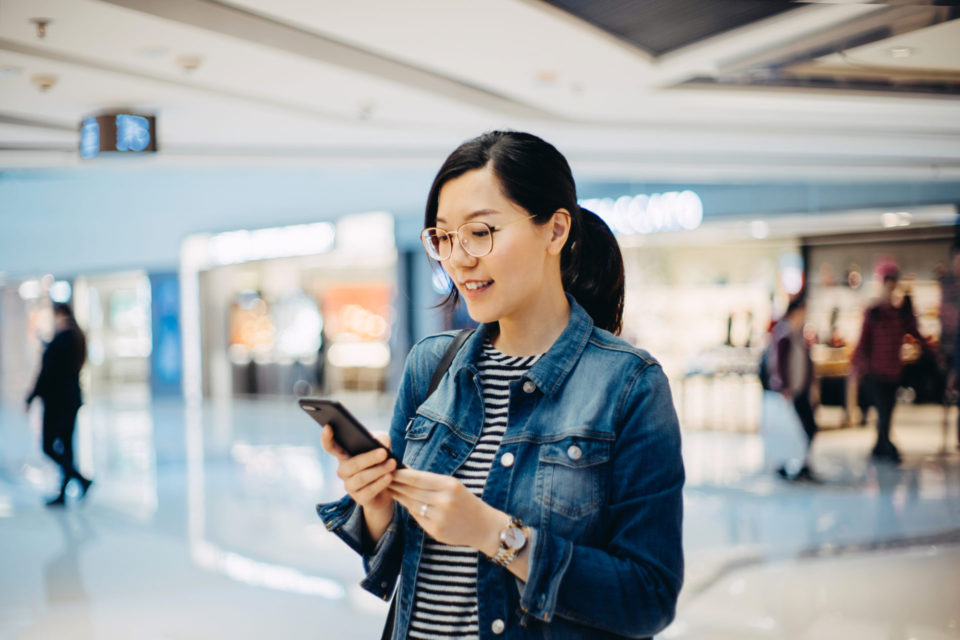 Young woman using smartphone in shopping mall