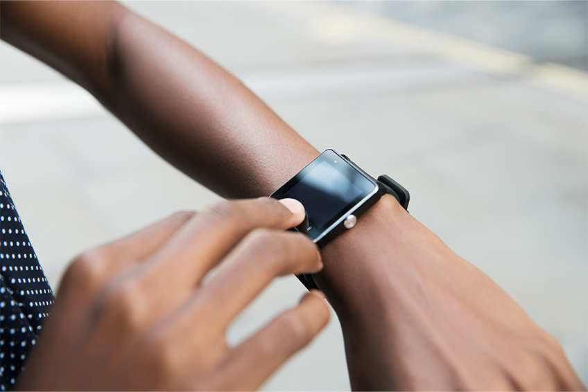 Image of a person's arm and hands while they look at a smart watch