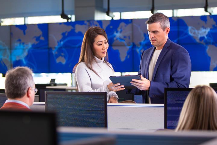 Team members talking at work stations