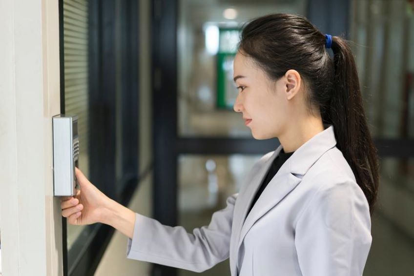 Woman in lab coat pressing button on wall