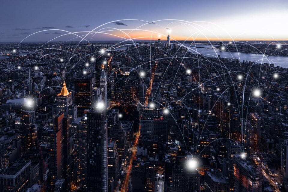 A vibrant city skyline at twilight, with interconnected white lines symbolizing a network overlaying the urban landscape