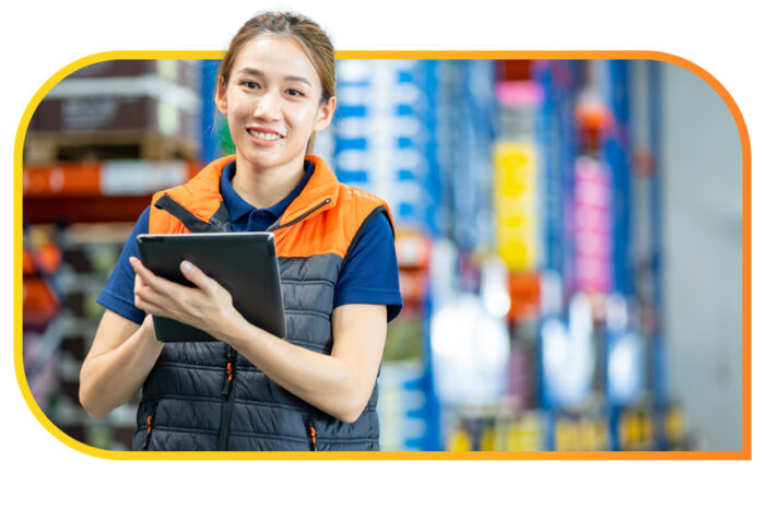 Woman stands inside a warehouse and works from her tablet